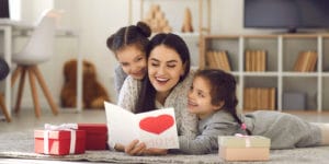 Twin sisters hugging their mom on Mother’s Day and giving them a creative Mother’s day gift