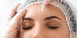A close-up of a woman receiving an injection on her forehead during a cosmetic procedure